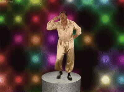 A Man In A Gold Jumpsuit Is Standing On A Podium In Front Of A Colorful Background . GIF