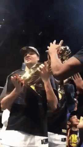 A Man In A Golden State Warriors Shirt Holds Up A Trophy GIF
