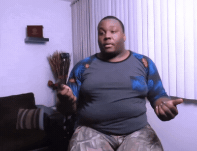 A Man In A Gray And Blue Shirt Is Holding A Sword GIF