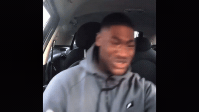 A Man In A Gray Hoodie Is Sitting In The Back Seat Of A Car . GIF