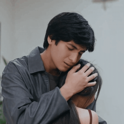 A Man In A Gray Jacket Holds A Woman In His Arms GIF