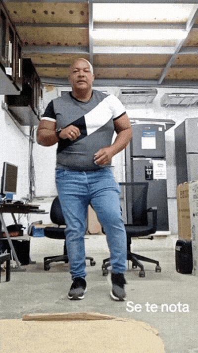 A Man In A Gray Shirt And Blue Jeans Is Dancing In A Room With The Words Se Te Nota Below Him GIF
