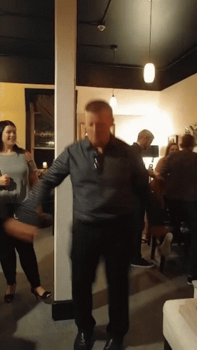 A Man In A Gray Shirt Is Dancing In A Room GIF