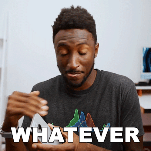 A Man In A Gray Shirt Is Holding A Cell Phone And The Word Whatever Is On The Bottom GIF