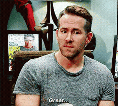 A Man In A Gray Shirt Is Sitting In A Chair And Saying Great GIF