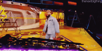A Man In A Gray Shirt With The Word Pay On It Walks On A Stage GIF