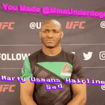 A Man In A Green And Black Shirt Is Standing In Front Of A Sign That Says Ufc GIF