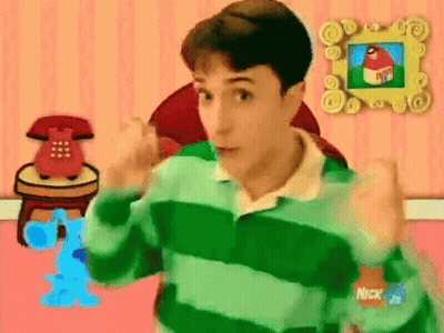 a man in a green and blue striped shirt is standing in front of a pink wall with a picture of a house on it .