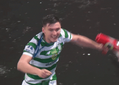 A Man In A Green And White Jersey With A Medal Around His Neck Holds A Red Can GIF