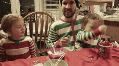 A Man In A Green And White Striped Shirt Is Sitting At A Table With Two Children And A Container Of Strawberry Yogurt GIF