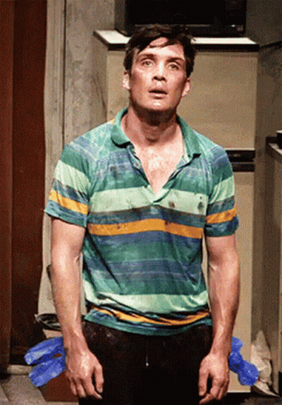 A Man In A Green And Yellow Striped Shirt Stands In Front Of A Refrigerator GIF