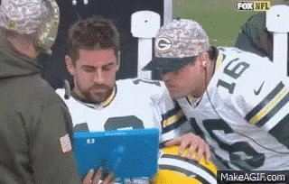 A Man In A Green Bay Packers Uniform Is Looking At A Tablet While Another Man Looks On . GIF