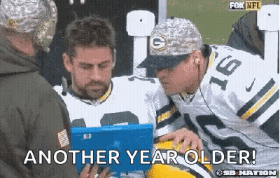 A Man In A Green Bay Packers Uniform Is Talking To Another Man While Holding A Tablet . GIF