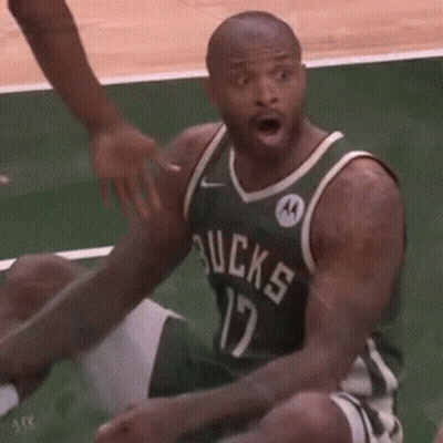 A Man In A Green Bucks Jersey Is Sitting On The Floor GIF