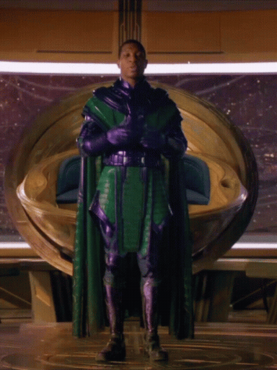 A Man In A Green Cape And Purple Gloves GIF