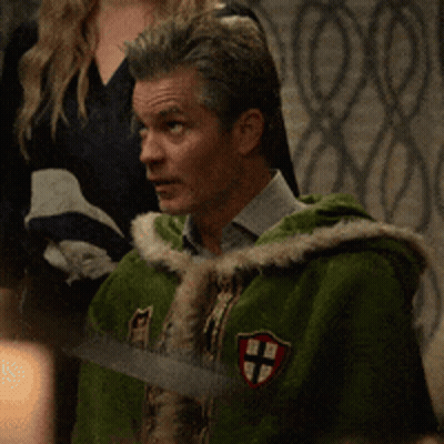 A Man In A Green Cape Has A Cross On His Chest GIF