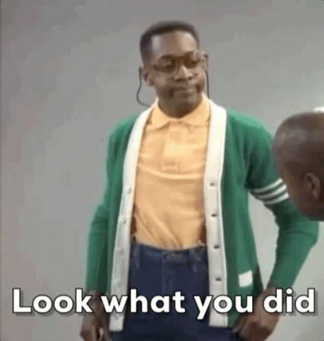 A Man In A Green Cardigan And Yellow Shirt Is Standing Next To Another Man . GIF