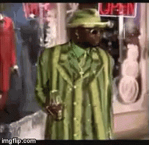 A Man In A Green Coat And Hat Is Standing In Front Of A Store Window . GIF
