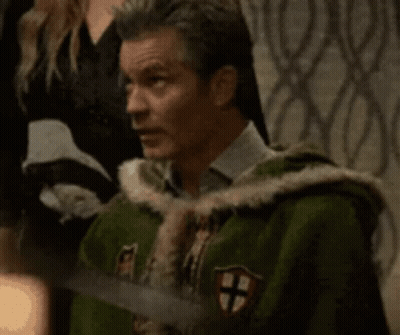 A Man In A Green Coat With A Cross On It Is Holding A Sword And Says I Know GIF