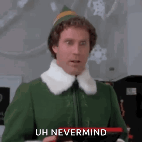 A Man In A Green Elf Costume Is Holding A Remote Control And Making A Surprised Face . GIF