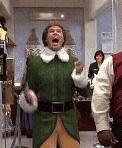 A Man In A Green Elf Costume Is Standing In A Room With His Mouth Wide Open . GIF