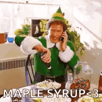 A Man In A Green Elf Costume Is Talking On A Cell Phone While Pouring Maple Syrup Into A Glass . GIF