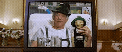 A Man In A Green Hat Is Sitting In A Hospital Bed Holding A Puppet . GIF