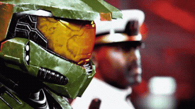 A Man In A Green Helmet Stands Next To Another Man In A White Uniform GIF