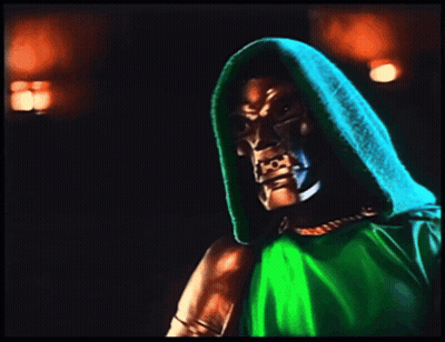 A Man In A Green Hooded Cape Holds A Fist In The Air GIF