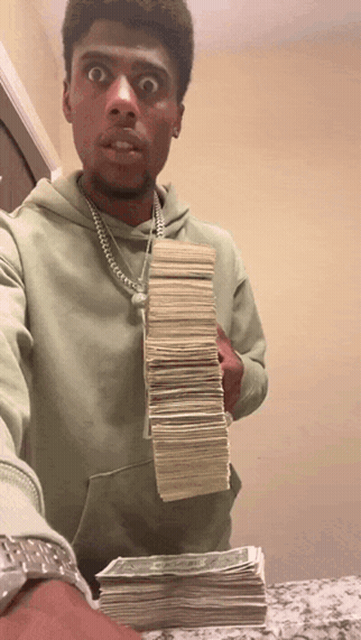A Man In A Green Hoodie Holds Up A Stack Of Money GIF