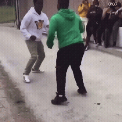 A Man In A Green Hoodie Is Dancing With Another Man GIF