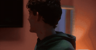 A Man In A Green Hoodie Is Standing In Front Of A Pink Wall GIF