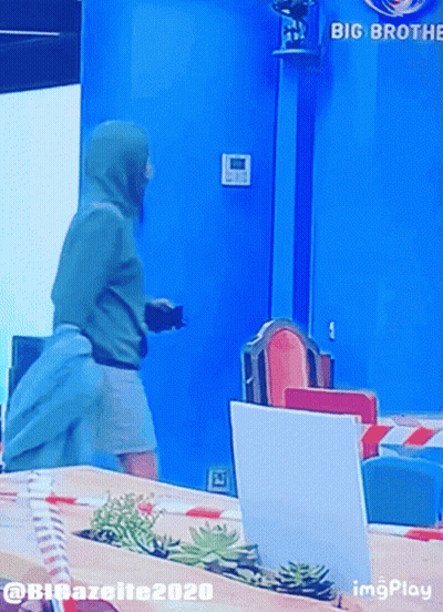 A Man In A Green Hoodie Is Standing In Front Of A Sign That Says Big Brother GIF