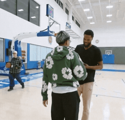 A Man In A Green Hoodie Is Talking To Another Man GIF