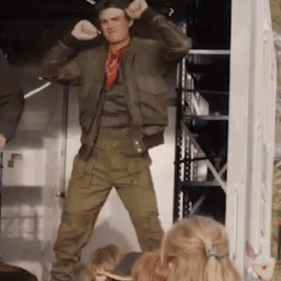 A Man In A Green Jacket Is Dancing In Front Of A Group Of Children GIF