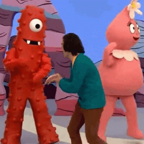 A Man In A Green Jacket Is Dancing With Two Cartoon Characters .. GIF