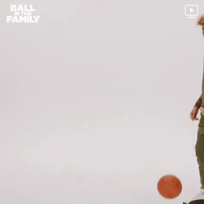 A Man In A Green Jacket Is Holding A Basketball In His Hand . GIF