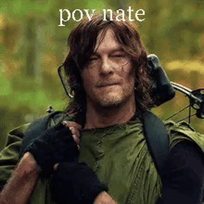 A Man In A Green Jacket Is Holding A Bow And Arrow And Wearing Headphones . GIF