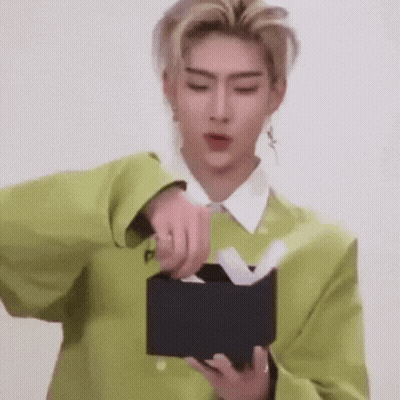 A Man In A Green Jacket Is Opening A Black Box With Tissues In It . GIF