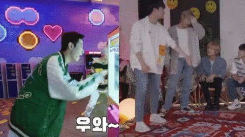A Man In A Green Jacket Is Playing A Video Game Next To A Group Of Young Men GIF