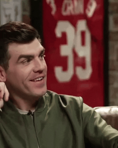 A Man In A Green Jacket Is Smiling In Front Of A Jersey With The Number 39 On It GIF