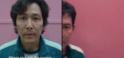 A Man In A Green Jacket Is Standing In Front Of A Pink Wall And Looking At The Camera . GIF