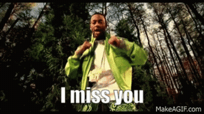 A Man In A Green Jacket Is Standing In The Woods With The Words `` I Miss You '' Written On The Screen . GIF