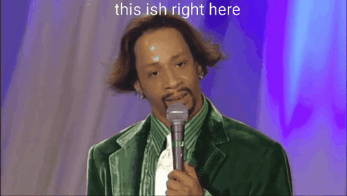A Man In A Green Jacket Is Standing On A Stage With A Microphone And The Words This Ish Right Here Above Him GIF