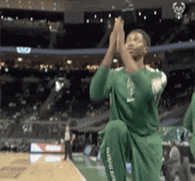 A Man In A Green Jersey Is Kneeling Down And Clapping GIF