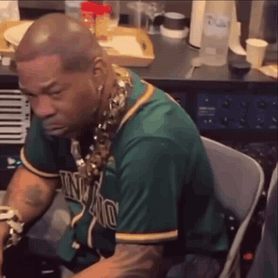 A Man In A Green Jersey Is Sitting In A Chair In Front Of A Piano . GIF