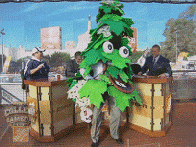 A Man In A Green Leafy Costume Stands In Front Of A Home Depot Sign GIF