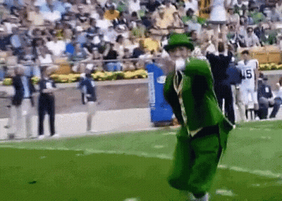 A Man In A Green Leprechaun Costume Is Throwing A Football On A Field GIF