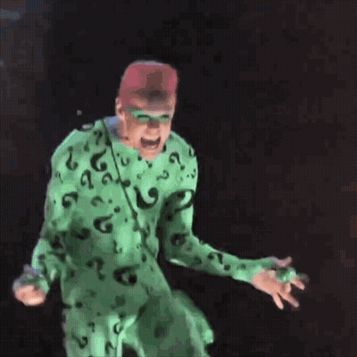 A Man In A Green Riddler Costume Is Standing On A Metal Surface GIF