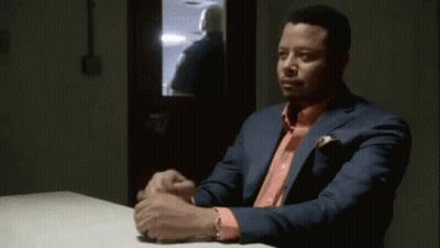 A Man In A Green Scrub Top Is Sitting At A Table With Another Man . GIF